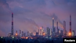 Gazele rezultate din ardere și aburul se ridică din coșurile unei rafinării de petrol din orașul siberian Omsk, Rusia, 8 februarie 2023.