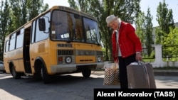 Egy nő táskákat cipel, miközben evakuálják Novaja Kahovkából, a kahovkai gát átszakadása nyomán keletkezett áradás elől