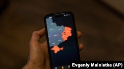 Okostelefon Kijevben 2023. március 27-én, a képernyőn az Air Alert alkalmazással, amely az orosz rakétatámadások alatt álló régiókat mutatja. Az Air Alert angol nyelvű változatának hangja Mark Hamill, a Csillagok háborúja színésze, aki nyugodt baritonhangon szólítja fel a lakosokat, hogy menjenek az óvóhelyre