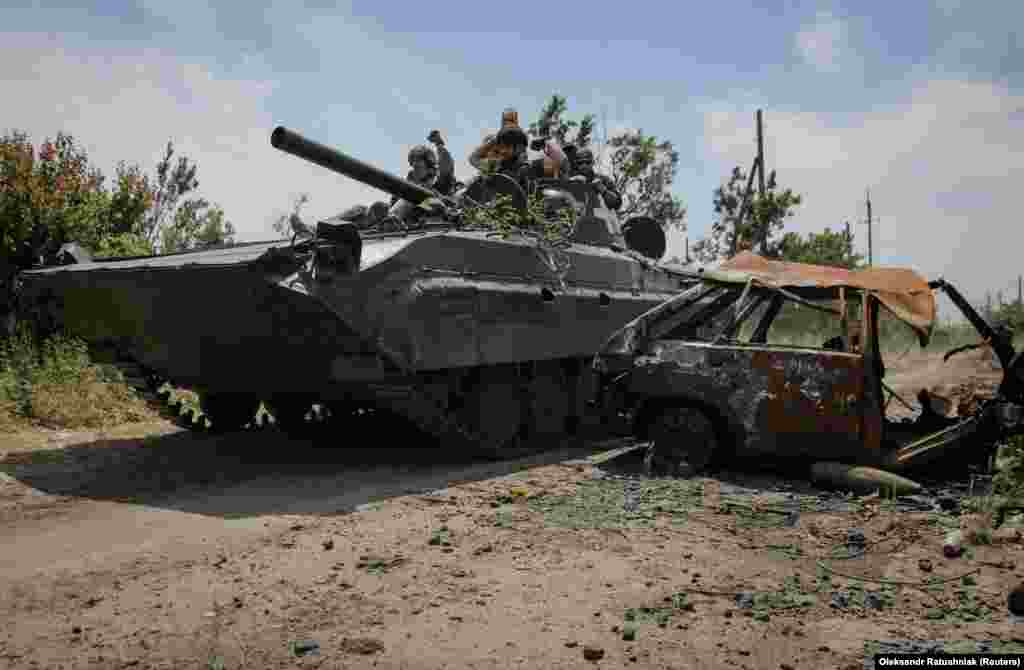 Украинские военные проезжают на БМП мимо разрушенной машины&nbsp;&nbsp;