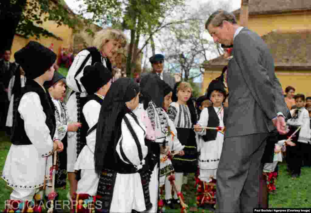 Charles și câțiva copii îmbrăcați în straie populare locale, Sibiu, 4 noiembrie 1998. Călătoria sa oficială din urmă cu aproape trei decenii în România a durat trei zile, timp în care a mers într-un adăpost de noapte pentru persoane vârstnice și nevoiașe din București și&nbsp;a vizitat orașul Sibiu, conform arhivei Agerpres Foto.