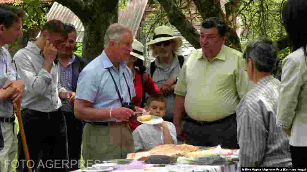 Aflat într-o vizită privată în Valea Zălanului, un sat izolat din județul Covasna, Charles discută cu localnicii și gustă bucate tradiționale, pe 29 mai 2014. Descrierea fotografiei menționează că, de câțiva ani, regele britanic obișnuia să vină pentru câteva zile de vacanță la conacul pe care îl deține și pe care l-a restaurat. În timp, el a cumpărat mai multe domenii și case tradiționale în județe precum Sibiu, Brașov ori Maramureș.
