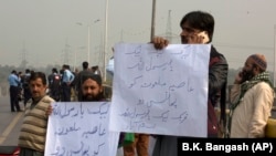 Supporters of a Pakistani religious group protest holding placards read "hang blasphemous Asia," as they blocked the main road to Islamabad on October 31.