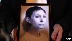 Портрет Виктории Рощиной в руках ее коллеги во время акции памяти о погибшей журналистки