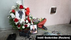 ლექსო ლაშქარავას ფოტო და დამსხვრეული კამერის ფრაგმენტები მისი დაკრძალვის დღეს, 2021 წლის 13 ივლისს 