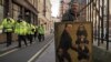 Человек с сатирическим портретом британского премьер-министра Дэвида Кэмерона ждет его прибытия в суд. Лондон, 14 июня 2012 года.