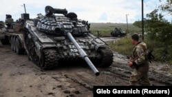 Украинские военнослужащие грузят трофейный российский танк на грузовик. Возле города Изюма Харьковской области, 24 сентября 2022 года 