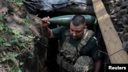 Военный 30-й ОМБр ВСУ несет снаряд для самоходной гаубицы 2С1 «Гвоздика» на передовой в Донецкой области, 13 августа 2025 года