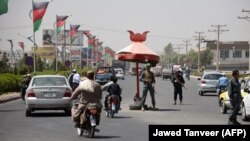 Afghan police stand guard at a checkpoint in Kandahar Province, the site of a deadly attack on October 18.