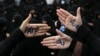 Hard-line Iranian protesters show their hands with writing in Persian that reads, "No to FATF," to protest the passage of a bill which joins Iran to the "Combating the Financing of Terrorism" on October 7.