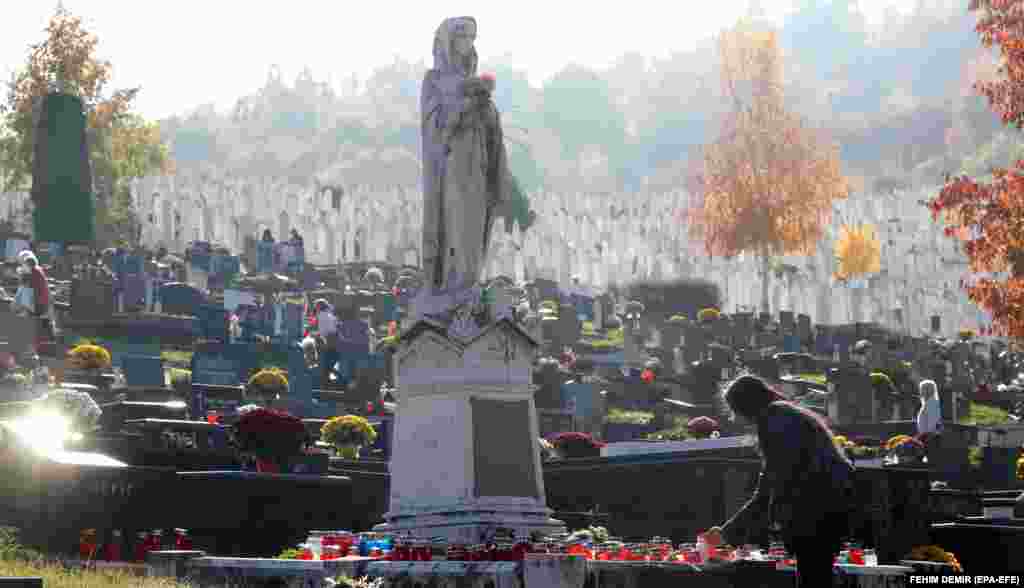 O credincioasă catolică bosniacă aprinde o lumânare la un mormânt din cimitirul Bare din Sarajevo pe 1 noiembrie.