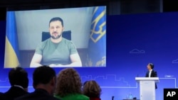 Volodimir Zelenszkij ukrán elnök videókapcsolaton keresztül vesz részt az országa helyreállításáról szóló konferencián. A jobb oldalon a házigazda, Rishi Sunak brit miniszterelnök látható 2023. június 21-én