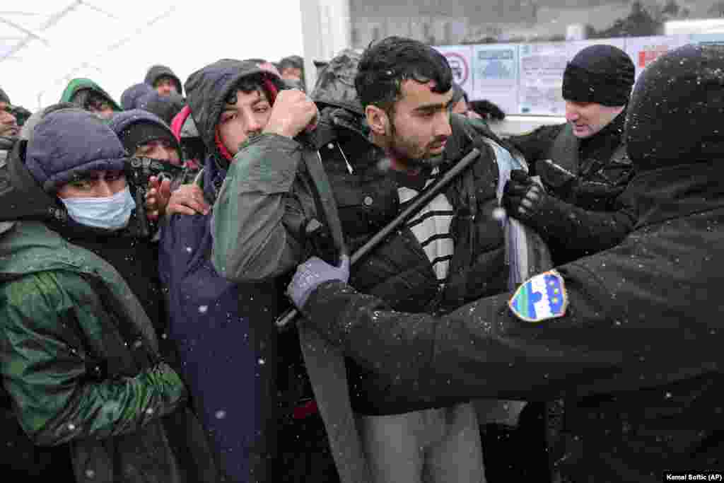 Un polițist față în față cu refugiații care așteaptă să fie mutați în tabăra de la Lipa pe 26 decembrie. Tabăra urma să fie închisă pe 23 decembrie și relocată. Cu toate acestea, oficialii au spus că operațiunea trebuie amânată, deși tabăra a fost distrusă aproape în totalitate în urma incendiului. Bosnia a devenit o piedică în calea miilor de migranți. Aceștia speră să ajungă în Croația vecină care este membră a Uniunii Europene și, de acolo, să se îndrepte către alte țări-membre ale UE occidentale.